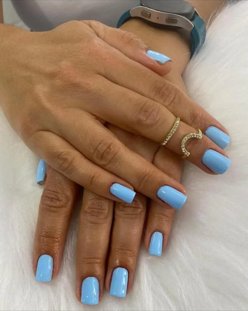 Mãos com unhas curtas esmaltadas em azul-claro